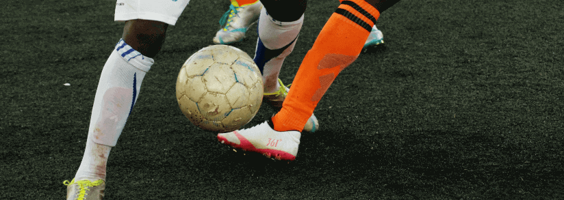 jogadores de futebol disputando bola grama meiao laranja branco