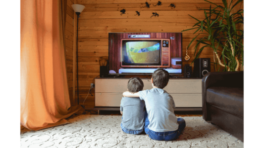 duas criancas assitindo tv abraçadas sala casa